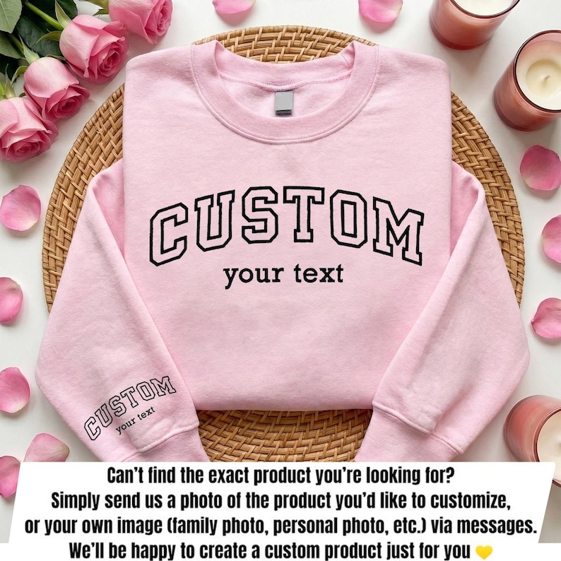 A pink sweatshirt with the text "CUSTOM your text" printed on it, along with a wicker basket and pink roses in the background.