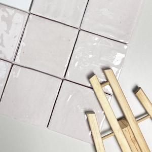 Puede incluir: Taza de cerámica blanca con asa negra y la frase "But First, Coffee" en negro. La taza se muestra sobre un fondo borroso, sugiriendo un ambiente acogedor.