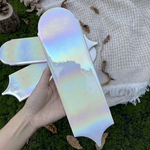 Puede incluir: Una taza de cerámica blanca con asa negra y el texto "But First, Coffee" en negrita negra. La taza se encuentra sobre un fondo borroso, sugiriendo un ambiente acogedor.