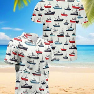 Op de afbeelding: Wit overhemd met korte mouwen met een patroon van vissersboten in rood, blauw en zwart. Het overhemd heeft een knoopsluiting en een kraag. De achtergrond toont een strandscène met palmbomen en de oceaan.