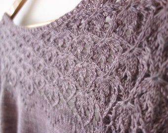 May include: A close-up of a mauve crocheted sweater with a delicate lace pattern.