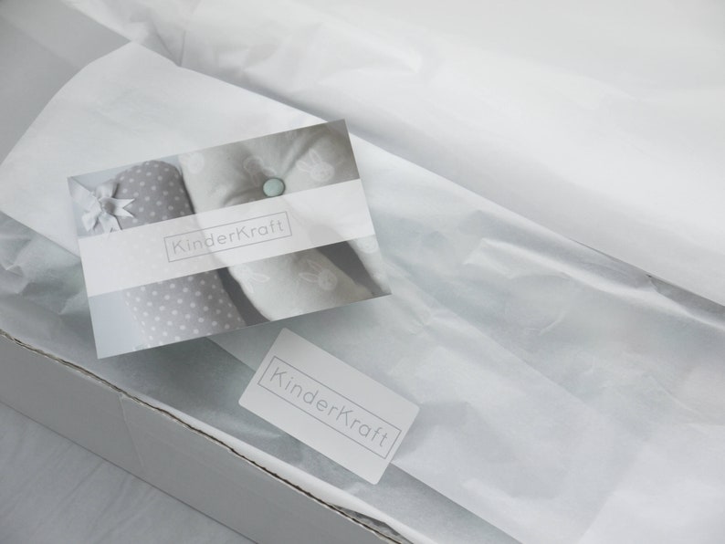 May include: A white box with a white tissue paper lining. The box has a white label with the text "KinderKraft" on it. The tissue paper is folded over the top of the box and has a white card with the text "KinderKraft" on it.