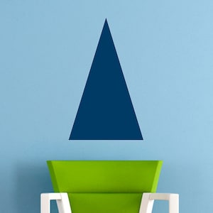 May include: A green and orange chair with white legs sits in front of a light blue wall with a dark blue triangle shape on the wall.
