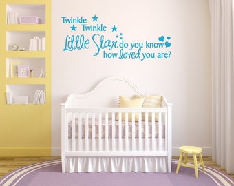 Peut inclure: Berceau blanc avec un drap à motifs violets et blancs et un tabouret jaune dans une chambre d'enfant avec un mur jaune et un mur blanc avec un autocollant mural bleu qui dit "Twinkle Twinkle Little Star do you know how loved you are?" avec des étoiles et des cœurs.