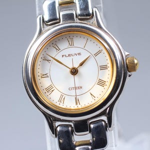 May include: A white ceramic mug with a black handle and the text "But First, Coffee" in a bold, black font. The mug is set against a neutral background, highlighting its simple design.