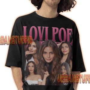 May include: Black t-shirt featuring a graphic of Lovi Poe with the text "LOVI POE" in pink. The shirt has a crew neck and short sleeves. The brand name "URBANSTUFFID" is printed on the shirt.