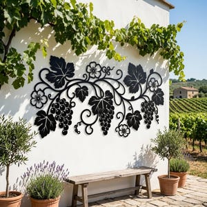 May include: A black metal wall art piece featuring a horizontal design of grapevines, including clusters of grapes, detailed leaves, and small flowers. The intricate cutout pattern is symmetrical and displays a botanical theme with curved stems.