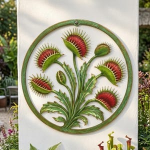 May include: A circular wall plaque featuring a relief sculpture of a Venus flytrap plant. The design displays green leaves and stems with multiple open traps showing red interiors and spiky edges, all enclosed within a weathered green frame.