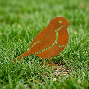 May include: A flat, two-dimensional metal garden ornament shaped like a robin bird. The object features a weathered, rusted brown finish with a cutout design that defines the bird's wing, chest, and eye, standing upright on a thin metal base.