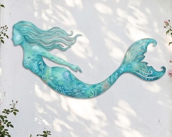 May include: A turquoise metal mermaid wall art piece. The mermaid has flowing hair and a detailed tail. The body of the mermaid is decorated with aquatic life, including fish and a seahorse. The art is mounted on a white wall.