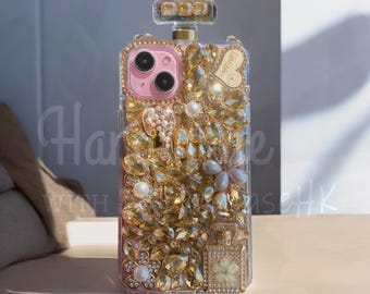 May include: A clear phone case with a pink camera frame, adorned with gold-colored rhinestones and pearls. The case is shaped like a perfume bottle and features a decorative top. The text "Har" and "Wish" are visible.