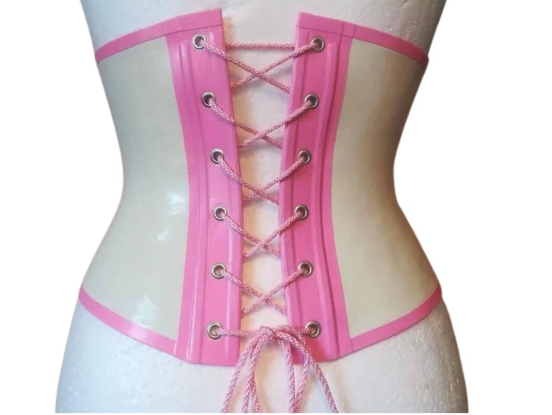 May include: A white latex corset with pink trim and a lace-up back. The corset has a smooth, shiny finish.
