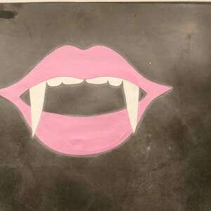 A pink mouth with white fangs on a dark gray background.