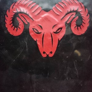 A red ram head with horns on a black background.