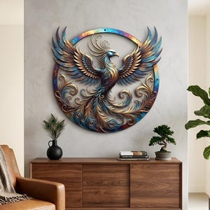 Könnte beinhalten: Ein detailliertes Metall-Wandkunstwerk, das einen Phönix mit ausgebreiteten Flügeln darstellt. Das Kunstwerk zeigt ein kreisförmiges Design mit dem Phönix in Blau-, Gold- und Bronzetönen. Der Vogel ist von kunstvollen, wirbelnden Details umgeben, was einen auffälligen Anblick erzeugt.