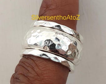 Può includere: Un anello in argento caratterizzato da una fascia centrale larga con texture martellata, affiancata da due fasce in argento più sottili e anch'esse martellate. Il testo SilversenthoAtoZ è visibile in giallo sopra l'anello. Tre fasce d'argento.