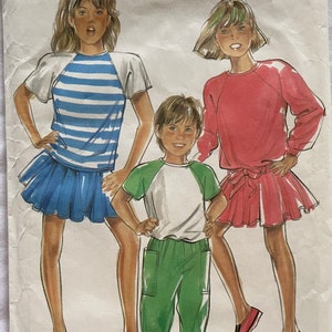Può includere: Un cartamodello per tre abiti, tra cui una camicia a righe e una gonna, un maglione rosso e una gonna, e una camicia verde e bianca con pantaloni verdi. Il cartamodello si chiama "New Look" e il numero è 6391.