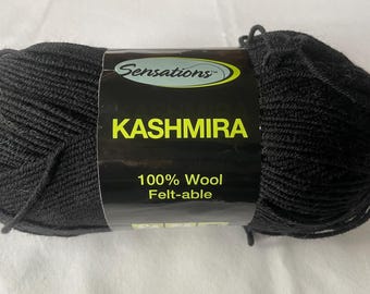 May include: A skein of black Kashmira yarn from Sensations. The label reads "Kashmira 100% Wool Felt-able". The yarn is tightly wound and appears soft, ideal for knitting or crocheting projects.