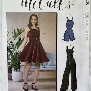 May include: McCall's sewing pattern featuring a burgundy velvet dress with a belt and a jumpsuit design. The pattern includes multiple view options and simple instructions. The text on the pattern reads "#LaylaMcCalls".