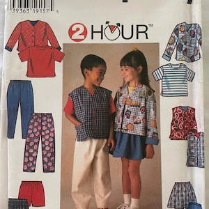 Op de afbeelding: Simplicity naaipatroon nummer 7229 voor kinderkleding. Het patroon bevat een vest, een jas, een broek, een rok en een short. Het patroon is voor maten 5, 6 en 6X. Het patroon is getiteld "2 uur" en heeft een klok met een wijzer die naar het getal 2 wijst.