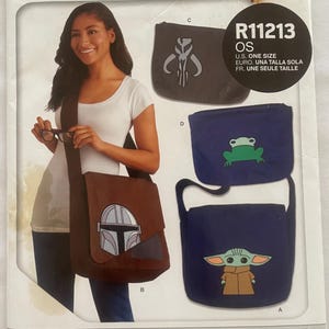 May include: A sewing pattern for messenger bags and laptop sleeves featuring characters from the Star Wars: The Mandalorian TV series. The pattern includes instructions for making four bags: a brown bag with the Mandalorian's helmet, a blue bag with a frog, a blue bag with Grogu, and a black bag with the Mandalorian's symbol. The pattern is labelled "R11213 OS" and is designed and printed in the USA.