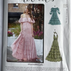 May include: McCall's sewing pattern featuring a pink off-the-shoulder maxi dress and two other dress designs. The pattern includes the text "#AuroraMcCalls" and is designed and printed in the USA.
