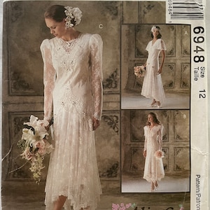 May include: A vintage McCall's pattern for a wedding dress, size 12, with three different styles. The dress is white lace with a high neckline and long sleeves. The pattern is called "Alicyn Exclusives" and the pattern number is 6948.