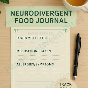 May include: A light green "Neurodivergent Food Journal" with prompts for tracking meals, medications, and sensory cues. A black pen and a cup of tea are next to the journal. The journal is on a light wood surface.