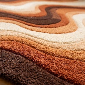 A close-up, angled view of the rug, showing the texture and wavy stripes in shades of brown, orange, and cream.