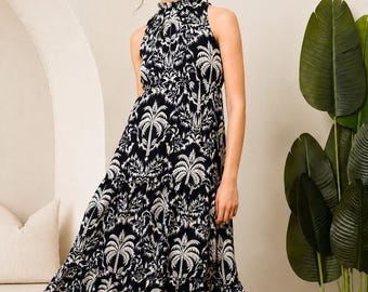 Könnte beinhalten: Ein ärmelloses Maxikleid mit hohem, gerafftem Kragen und einem gestuften Rock. Das Kleidungsstück ist durchgehend mit einem sich wiederholenden schwarz-weißen Muster aus Palmen und tropischem Blattwerk bedruckt.