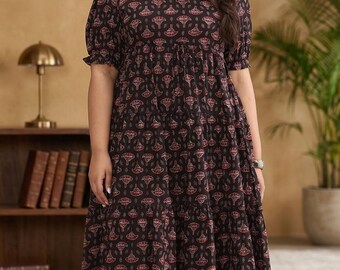 Könnte beinhalten: Ein schwarzes Midikleid mit einem sich wiederholenden rosa-weißen Blumenmuster, einem V-Ausschnitt und kurzen Puffärmeln mit elastischen Bündchen. Das Kleid hat einen gestuften Rock mit geraffter Taille und eine lockere, fließende Silhouette.