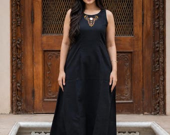 Könnte beinhalten: Eine ärmellose, wadenlange schwarze Tunika mit einem Rundhalsausschnitt, der mit goldfarbenen Stickereien und kleinen runden Spiegeln verziert ist. Dazu wird eine passende schwarze Hose mit weitem Bein kombiniert, was ein schlichtes Set ergibt.