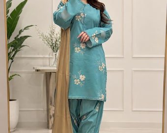 Könnte beinhalten: Eine langärmelige Tunika in Blaugrün und eine passende Faltenhose mit weißem Blumenmuster. Das Outfit enthält eine einfarbige, beige, transparente Dupatta, die über einer Schulter liegt. Die Tunika hat einen Rundhalsausschnitt und einen gesäumten Saum.