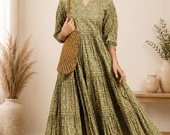 Könnte beinhalten: Ein olivgrünes Midikleid mit weißem geometrischem Blockdruckmuster, V-Ausschnitt, Dreiviertelärmeln und einem gestuften Rock. Das Kleid wird mit einer braunen, gewebten Umhängetasche und hellen Riemchensandalen kombiniert.
