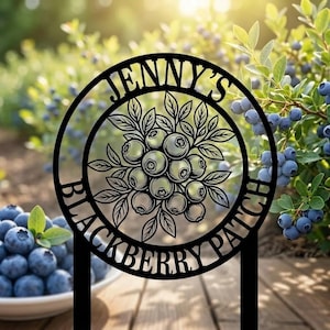 May include: Black metal sign with the text "JENNY'S BLACKBERRY PATCH" in a circular design, featuring a cluster of blueberries and leaves. The sign is displayed outdoors with a blurred background of blueberry bushes and a bowl of blueberries.