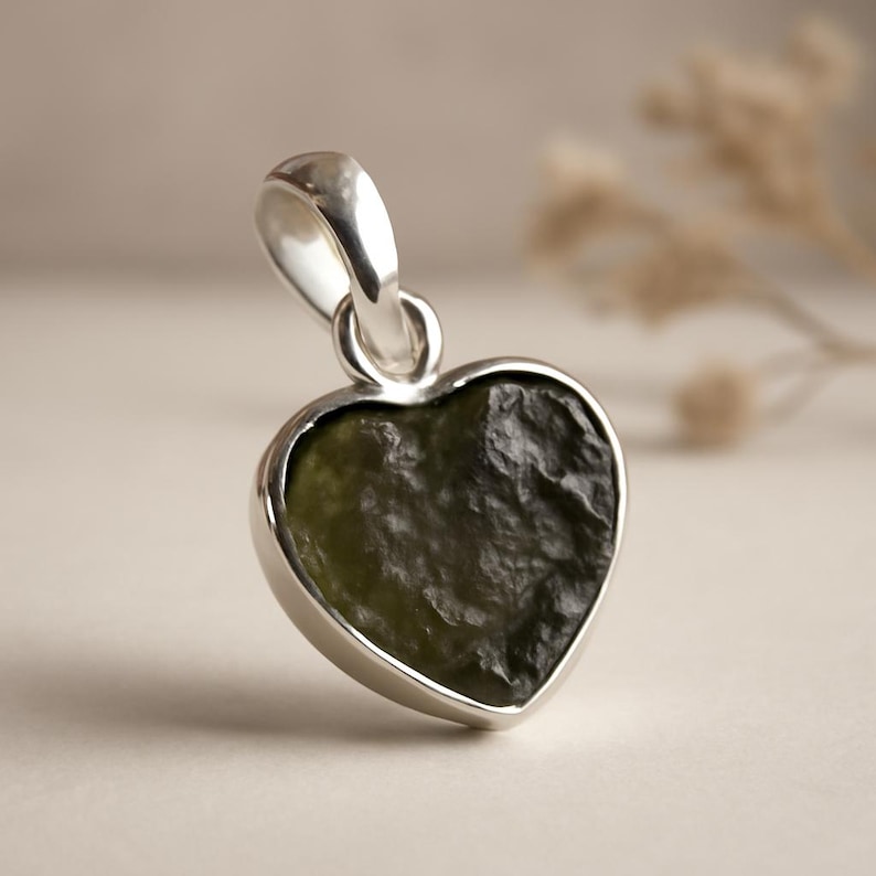 Peut inclure: Pendentif en forme de c&oelig;ur avec une monture argent&eacute;e. Le pendentif pr&eacute;sente une pierre textur&eacute;e vert fonc&eacute;. La b&eacute;li&egrave;re est &eacute;galement argent&eacute;e. Le pendentif est probablement destin&eacute; &agrave; un collier et est pr&eacute;sent&eacute; sur un fond neutre.