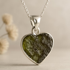 Peut inclure: Un collier pendentif en forme de c&oelig;ur avec une pierre vert olive textur&eacute;e sertie dans un cadre en m&eacute;tal argent&eacute;. Le pendentif est suspendu &agrave; une fine cha&icirc;ne argent&eacute;e, cr&eacute;ant un design simple mais &eacute;l&eacute;gant.