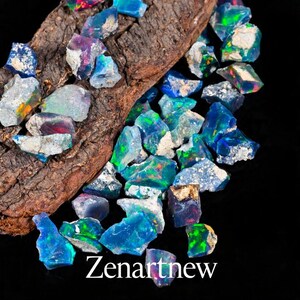 May include: A collection of raw, uncut opals in shades of blue, green, and purple, resting on a piece of dark brown wood. The opals have a shimmering, iridescent quality. The text "Zenartnew" is displayed in white at the bottom.