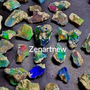 May include: A collection of raw opal stones with vibrant colors, including blues, greens, and reds. The opals have a rough, natural texture and are scattered across a dark surface. The text "Zenartnew" is visible.