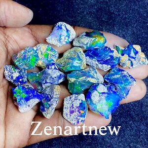 May include: A collection of rough opal gemstones with vibrant blue, green, and yellow flashes. The opals are held in a hand, showcasing their natural, irregular shapes and textures. The text "Zenartnew" is visible at the bottom.