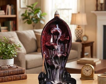 May include: A dark red and black ceramic incense burner shaped like a leaf with a central channel. A lit incense cone sits at the top, producing a white smoke trail that flows downward over sculpted petal-like tiers into a basin at the base.