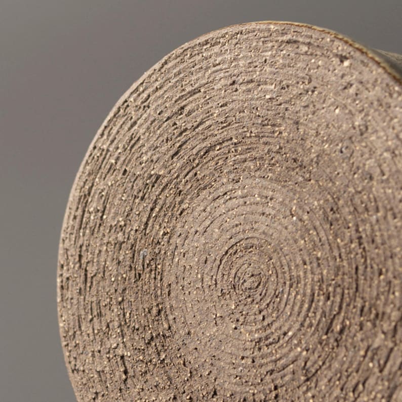Close-up of the unglazed ceramic mug base showing natural clay rings and handmade marks