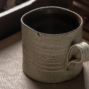 Close-up of the ceramic mug rim showing natural glaze variation and dark interior finish