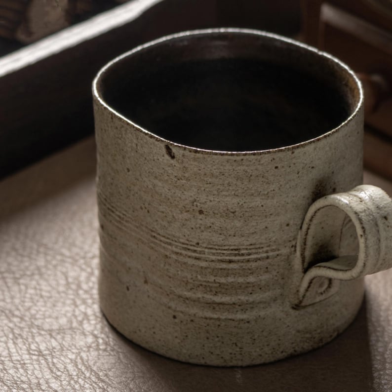 Close-up of the ceramic mug rim showing natural glaze variation and dark interior finish
