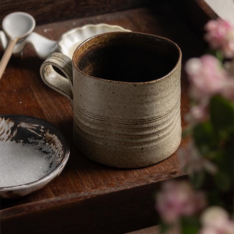 Rustic ceramic mug styled on a wooden table with soft shadows, emphasizing a calm wabi-sabi aesthetic