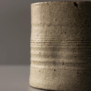 Detail view of the stoneware mug surface highlighting speckled glaze and wheel-thrown lines