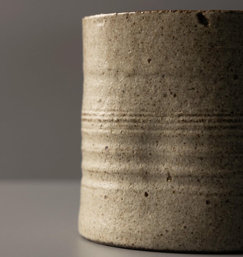 Detail view of the stoneware mug surface highlighting speckled glaze and wheel-thrown lines