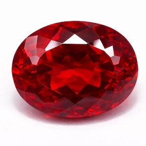 May include: A faceted, oval-shaped, red gemstone. The gem has a brilliant, reflective surface with multiple facets that catch and reflect light. The deep red color is consistent throughout the stone, creating a vibrant and eye-catching appearance.