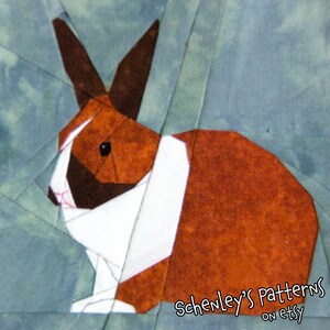 A photo of a quilt block made with this pattern.  A rabbit is seen from the side.  It has dutch coloring, brown fur with a white band across its chest and a white stripe on its head.