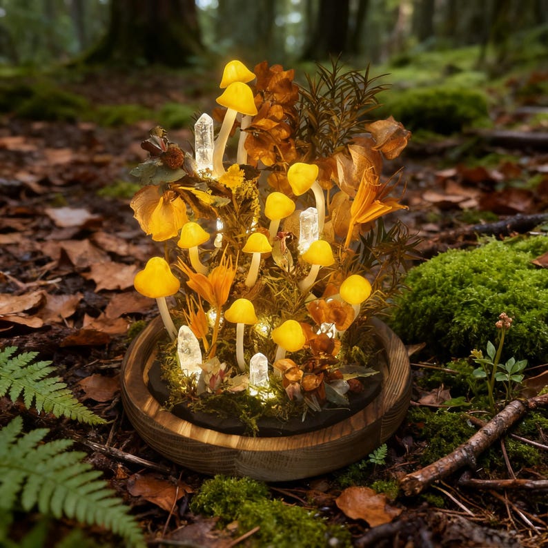May include: A decorative terrarium featuring glowing yellow mushrooms, clear quartz crystals, and dried foliage. The arrangement is set in a wooden bowl, creating a whimsical forest scene. The terrarium is illuminated with small lights, enhancing the magical aesthetic.